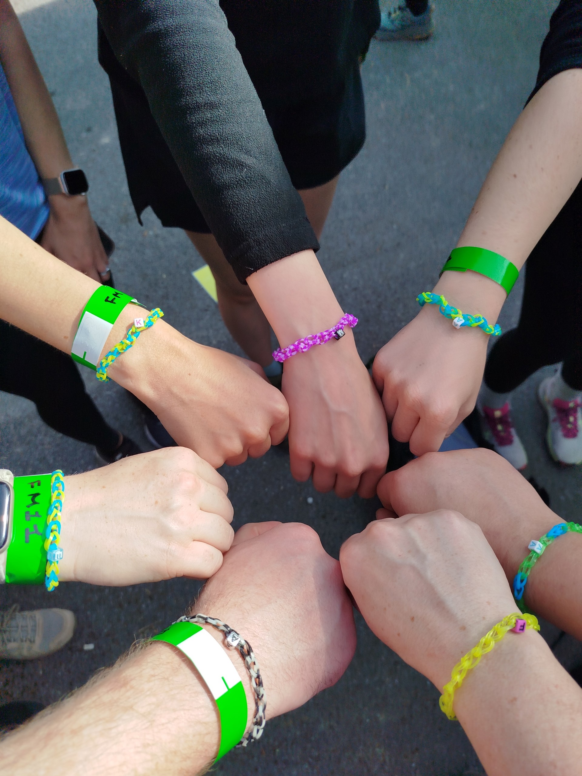 Seven hands showing bracelets which are a tribute to their colleague who died.