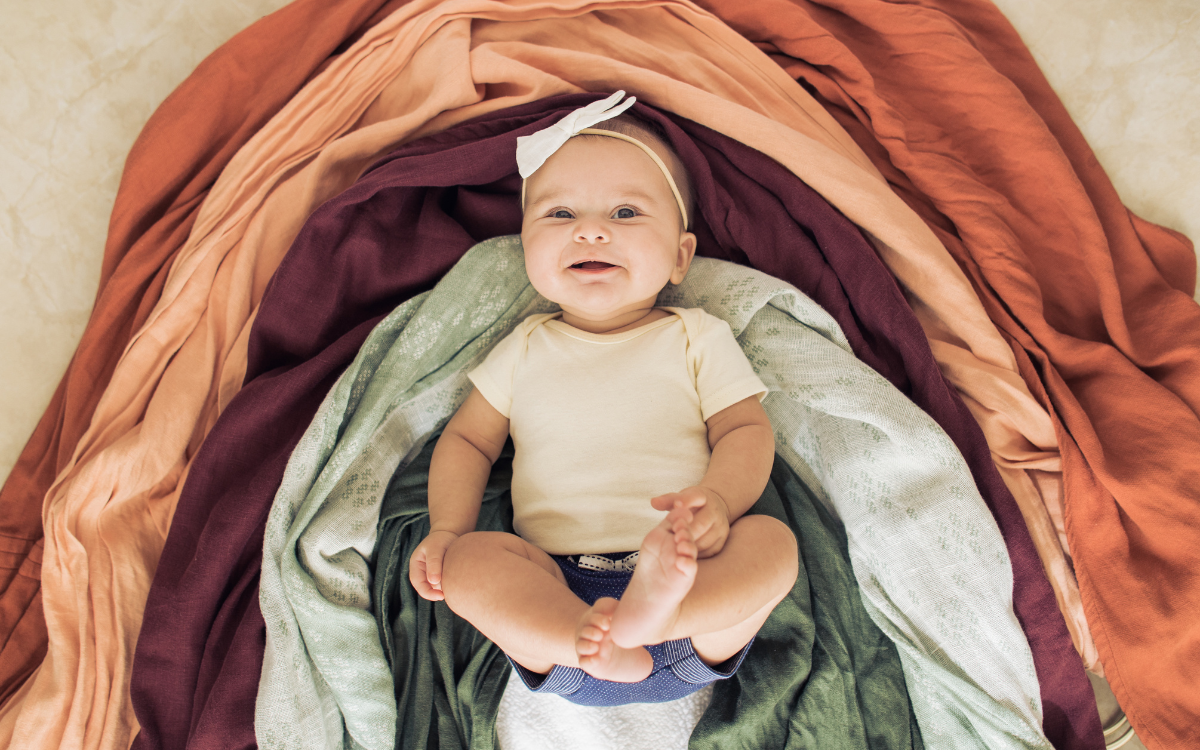 Baby in the middles of a rainbow made of cloth.