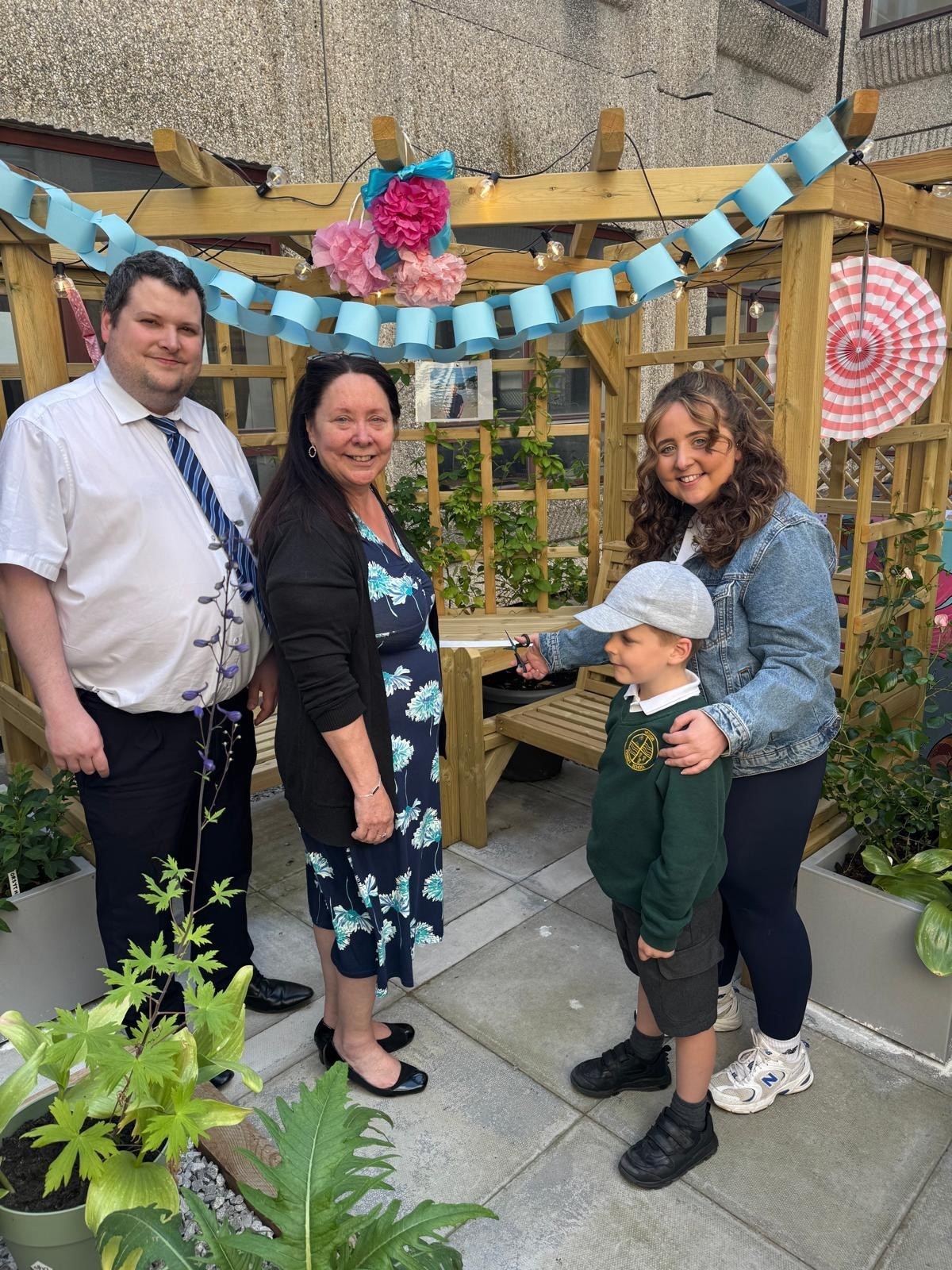 A man, two women and a child (Trevor's family) cutting a ribbon with scissors at the radiology garden.