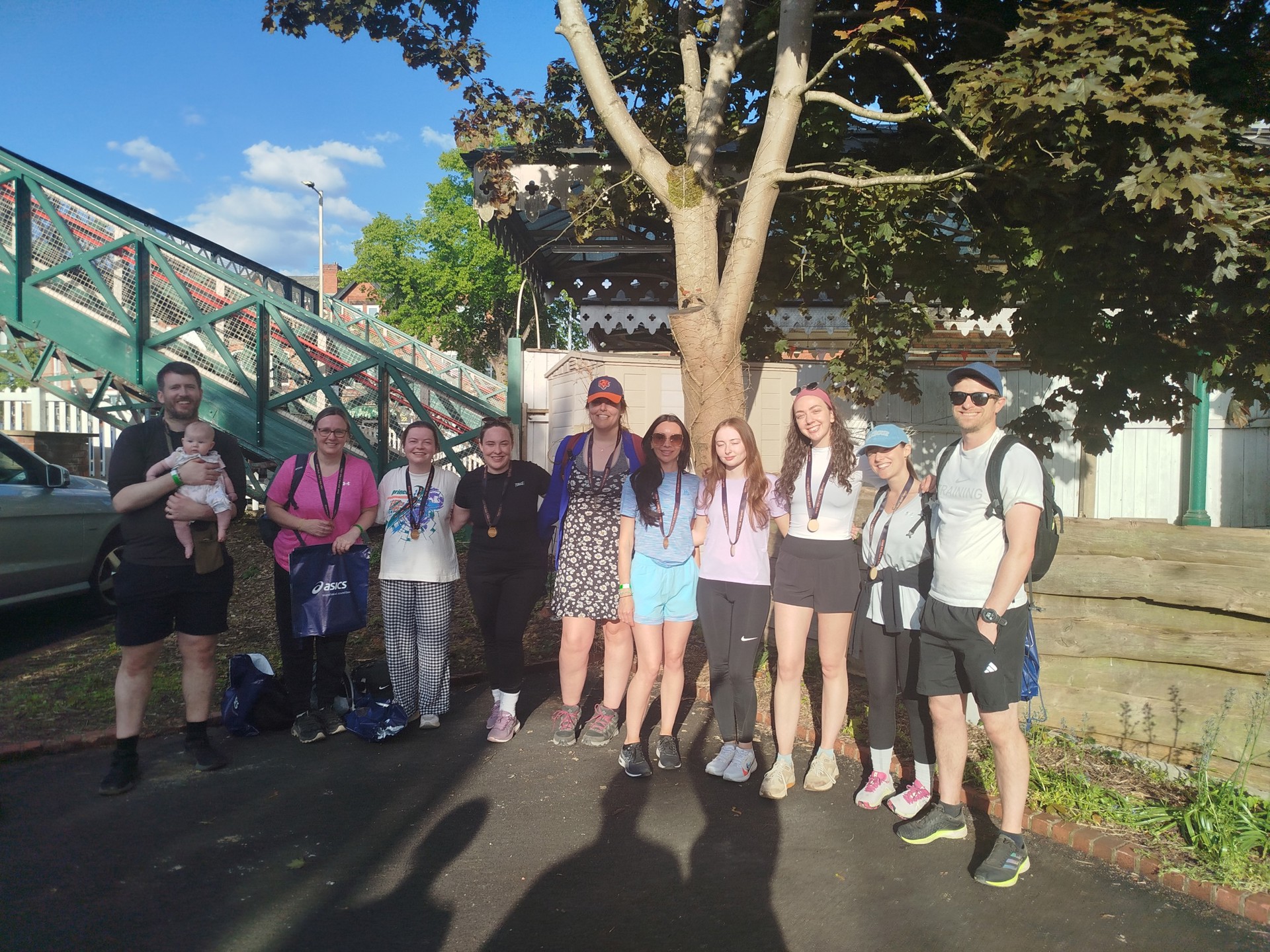 Ten members of the Ophthalmology Department and a baby smiling at the end of a 42km walking challenge.