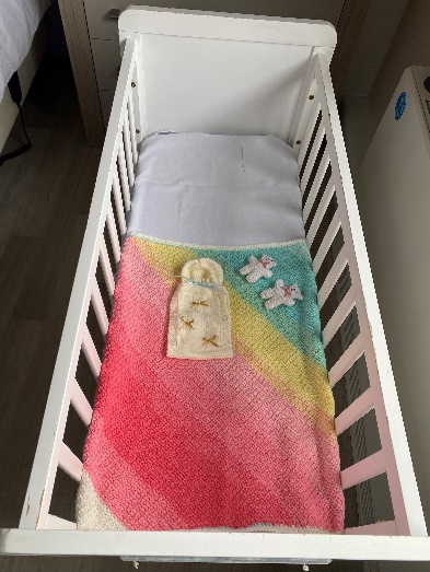 Cot with knitted blanket and bears.