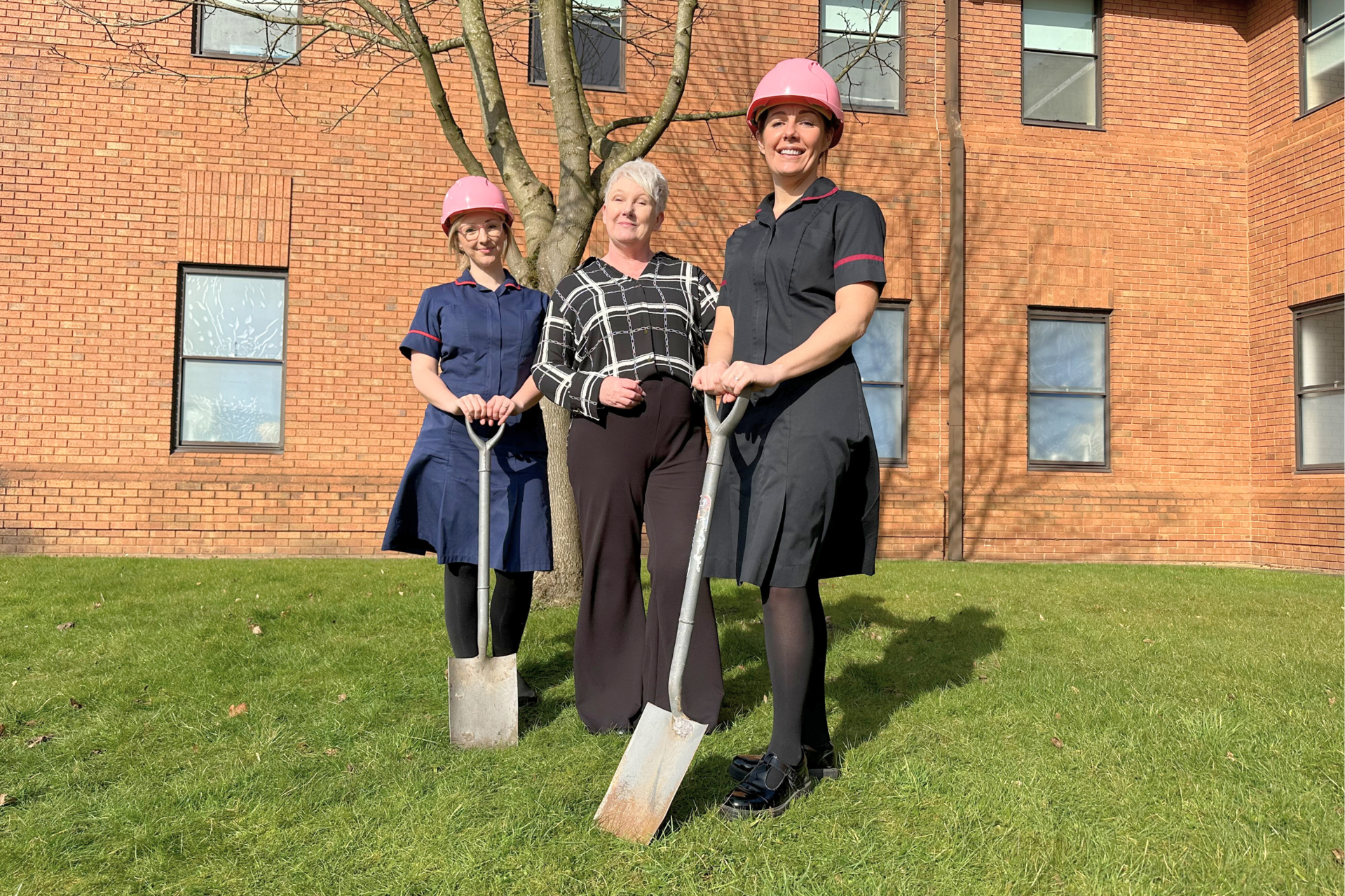 Three members of the Willow Tree Hub campaign team. The team are wearing pink hard hats at the location of the hub.