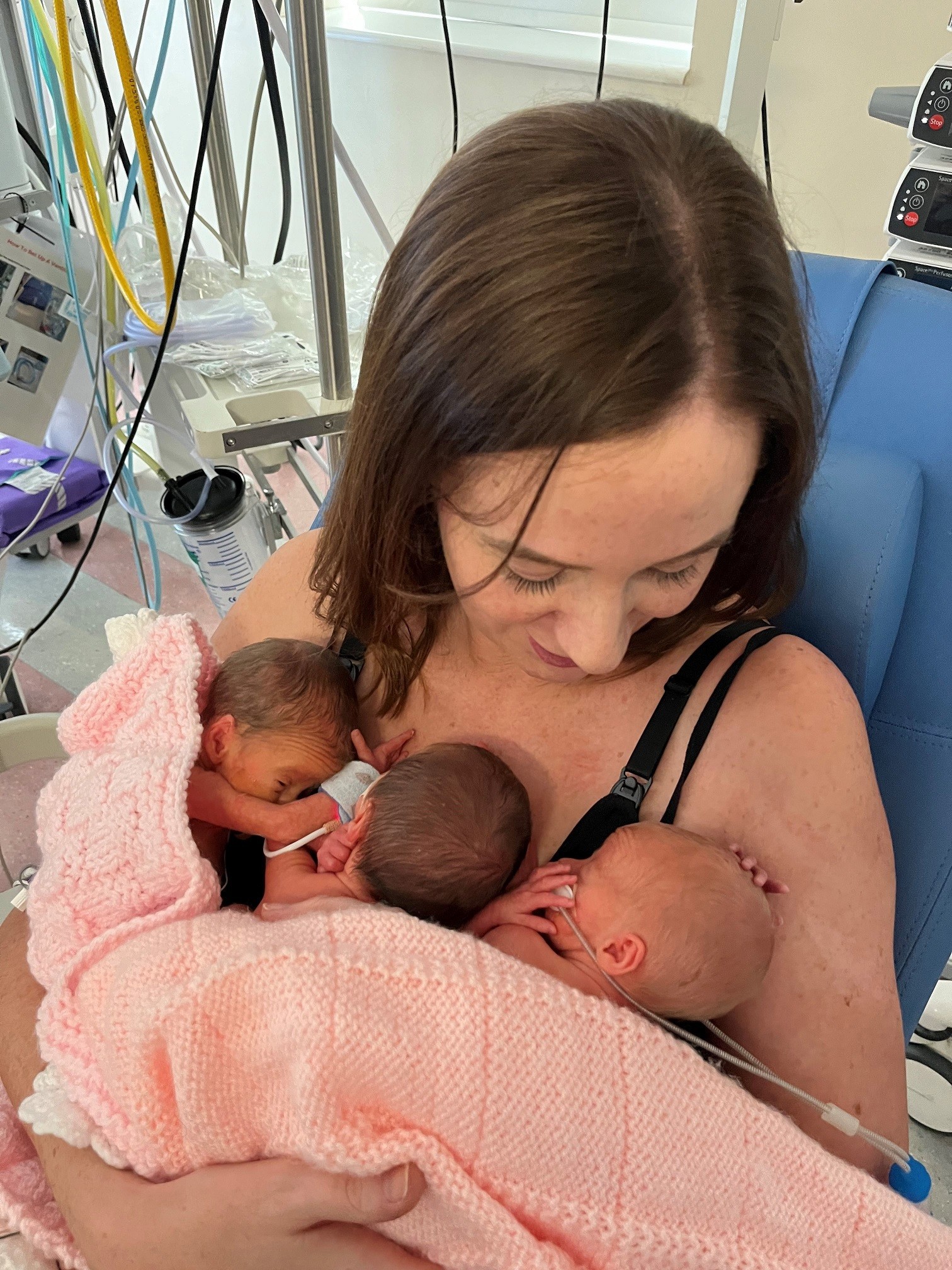 Two of three triplets being held by their older sister.